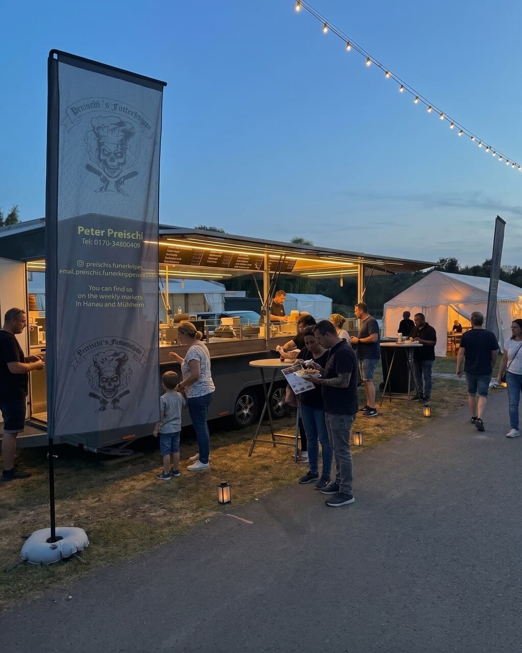 Foodtruck bei einem Event in der Abenddämmerung mit Lichterketten
