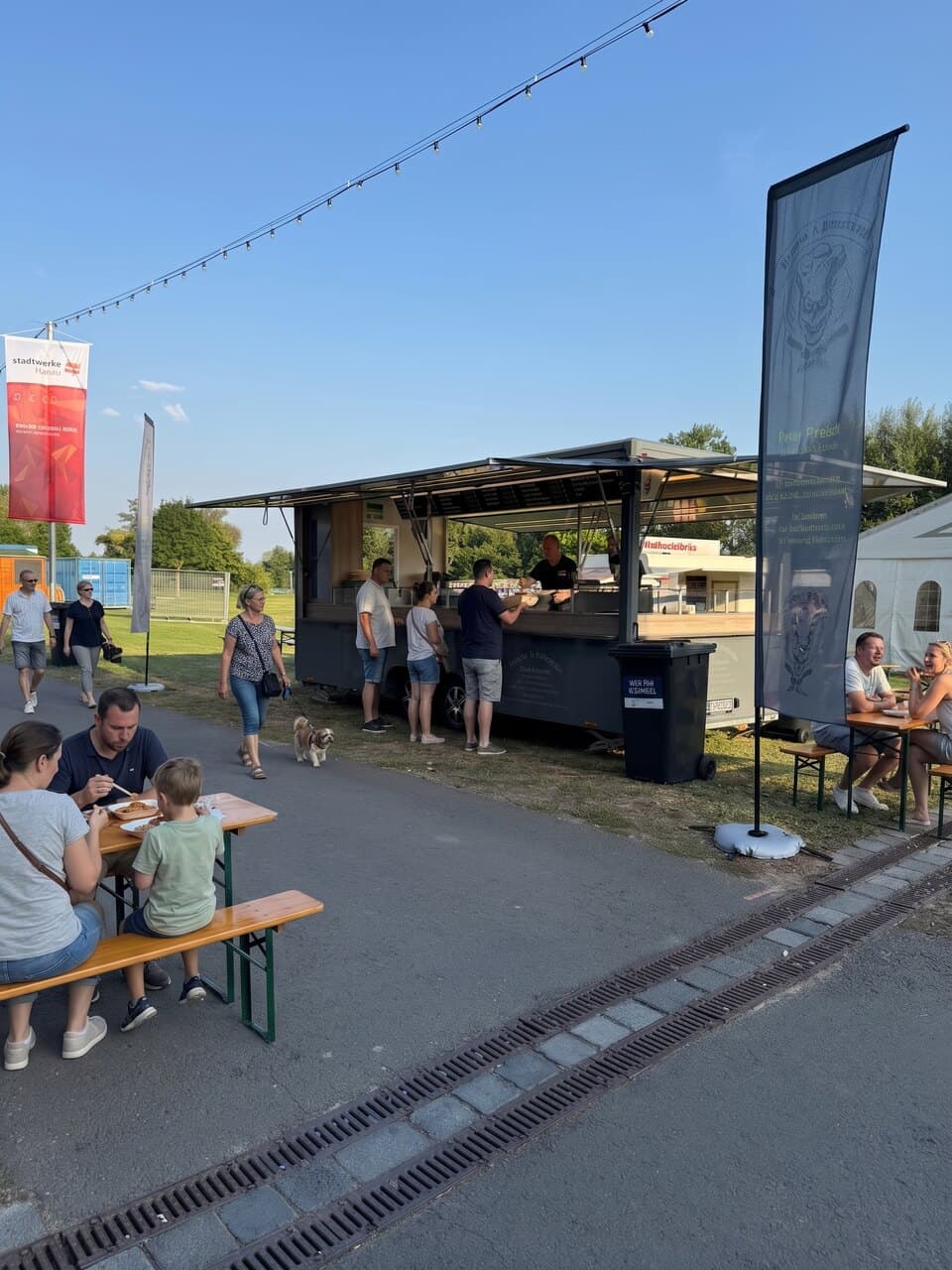 Foodtruck auf einem Sommerfest in Hanau, Familien an Biertischen bei blauem Himmel