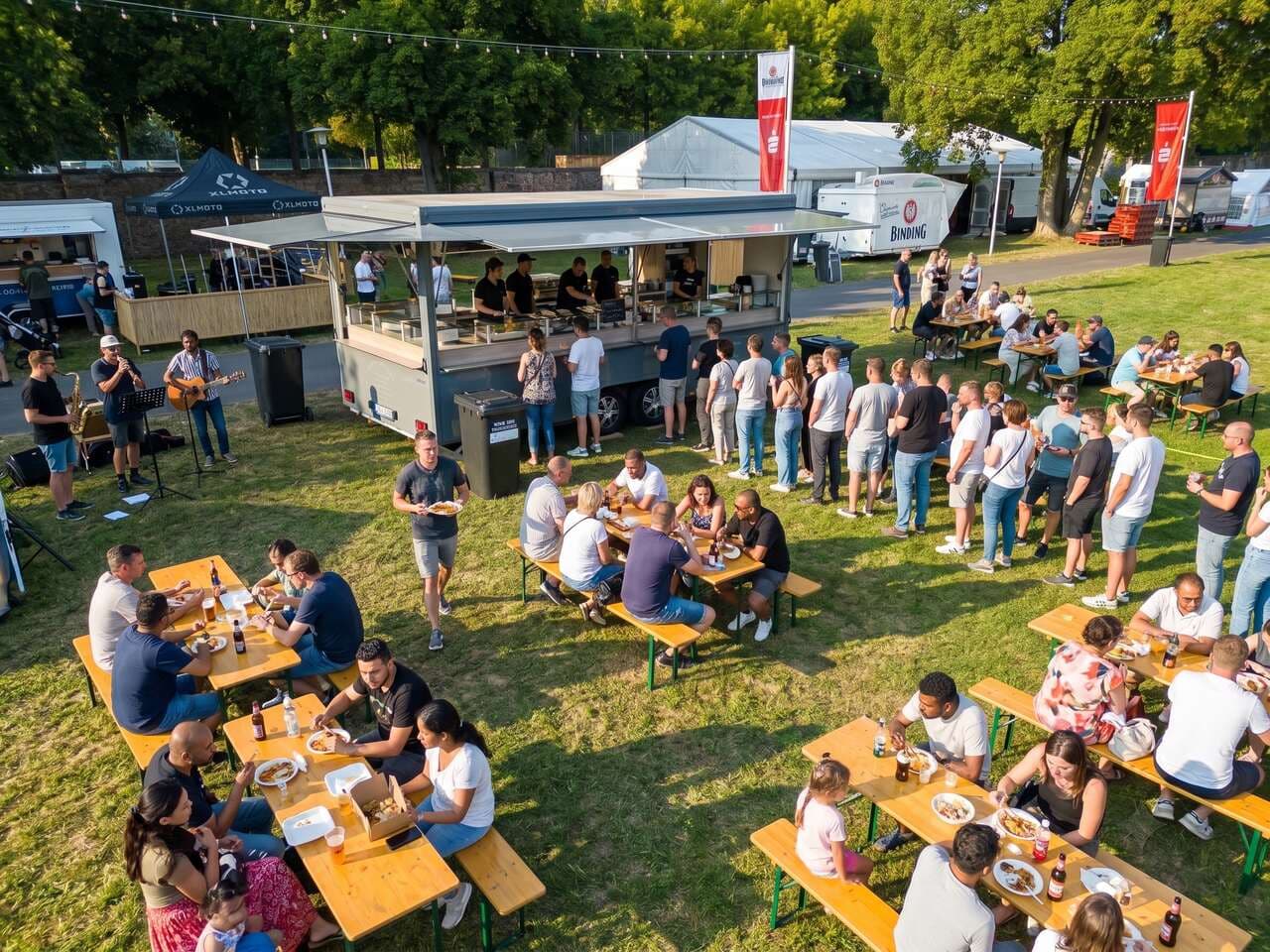 Foodtruck beim Sommerfest aus der Höhe, voll besetzte Biergarnituren und Live-Musik