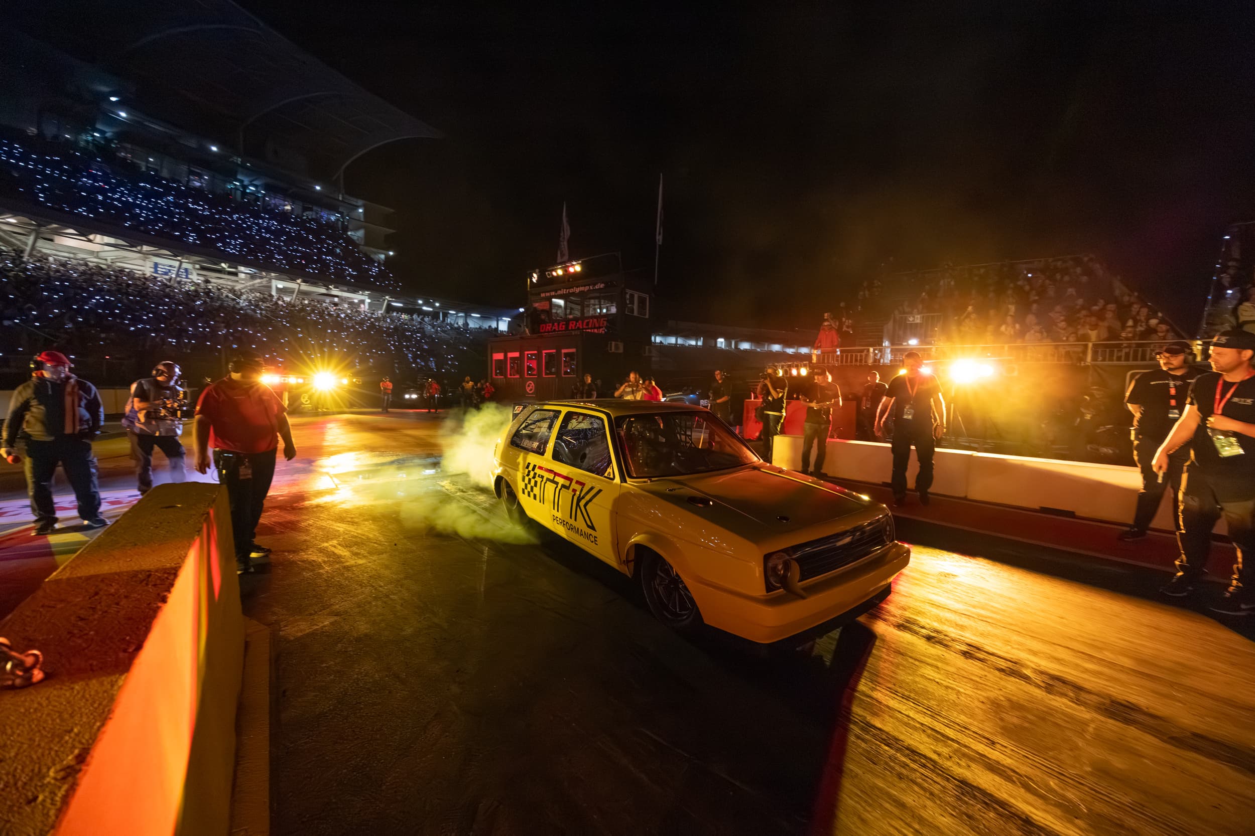 Nachtrennen bei den NitrOlympX 2025 — Dragster mit leuchtenden Flammen im Dunkeln